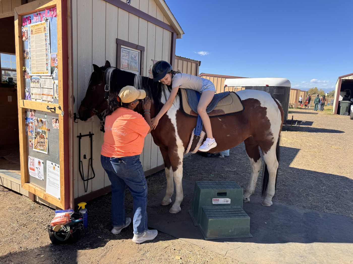 Carla helping a young rider settle into the saddle at the mounting block