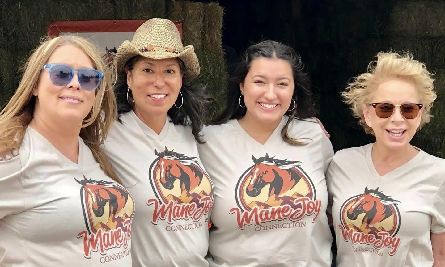 Four smiling Mane Joy Connection supporters in matching MJC T-shirts